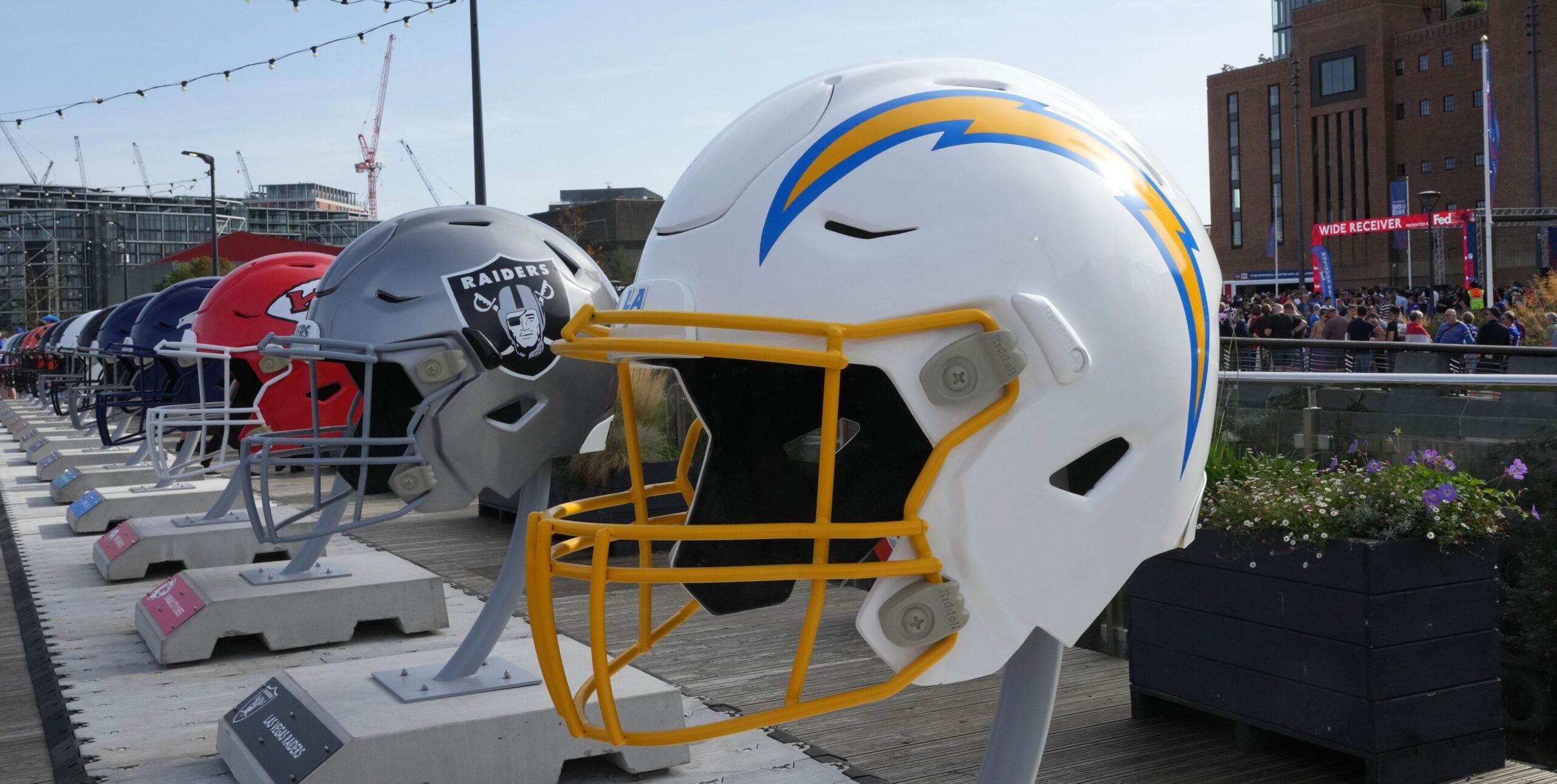 Oversized Chargers, Raiders, and Chiefs helmets displayed at NFL Experience London event at Battersea Power Station.