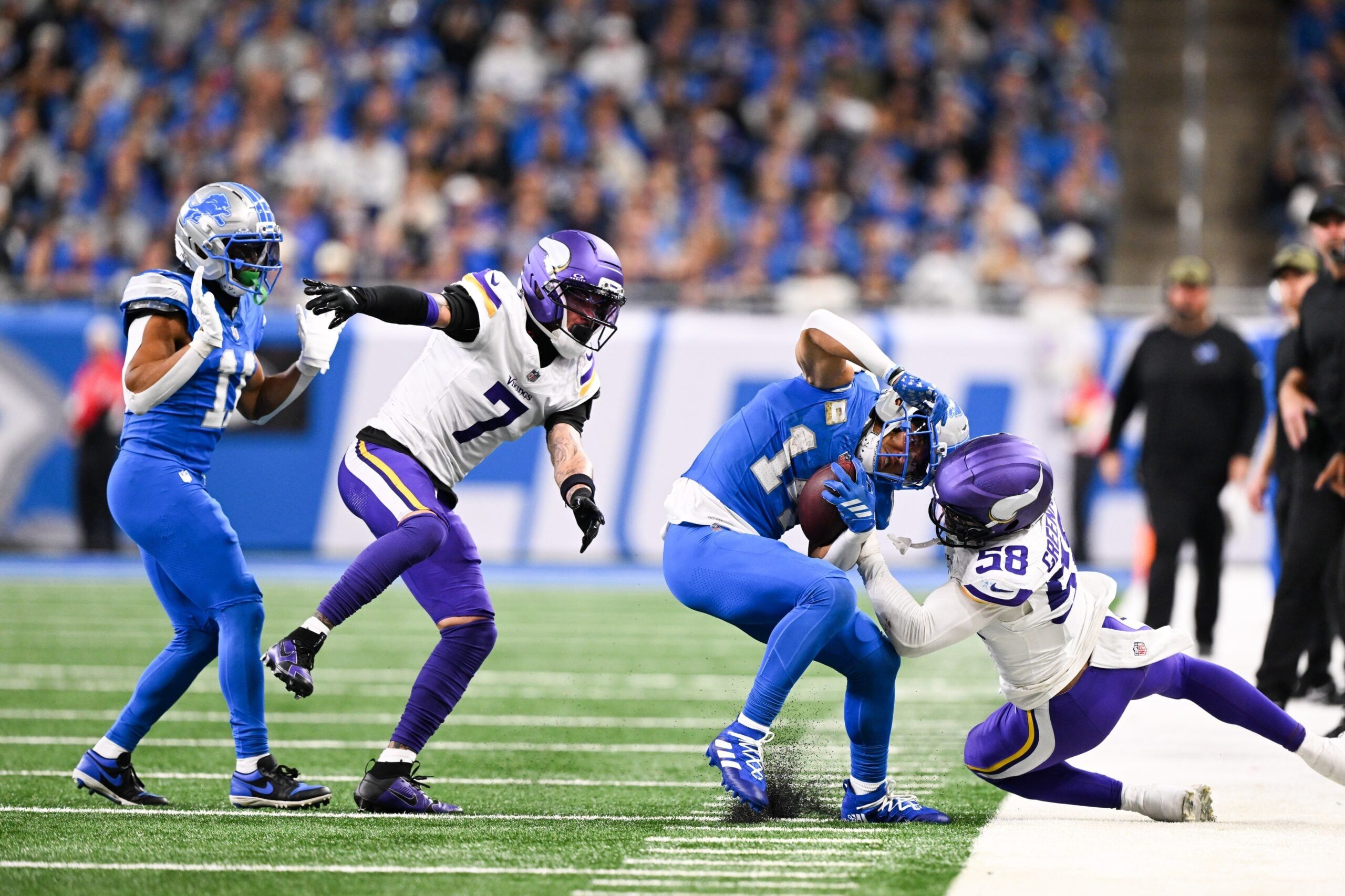 Amon-Ra St. Brown is pushed out of bounds by Jonathan Greenard during a game