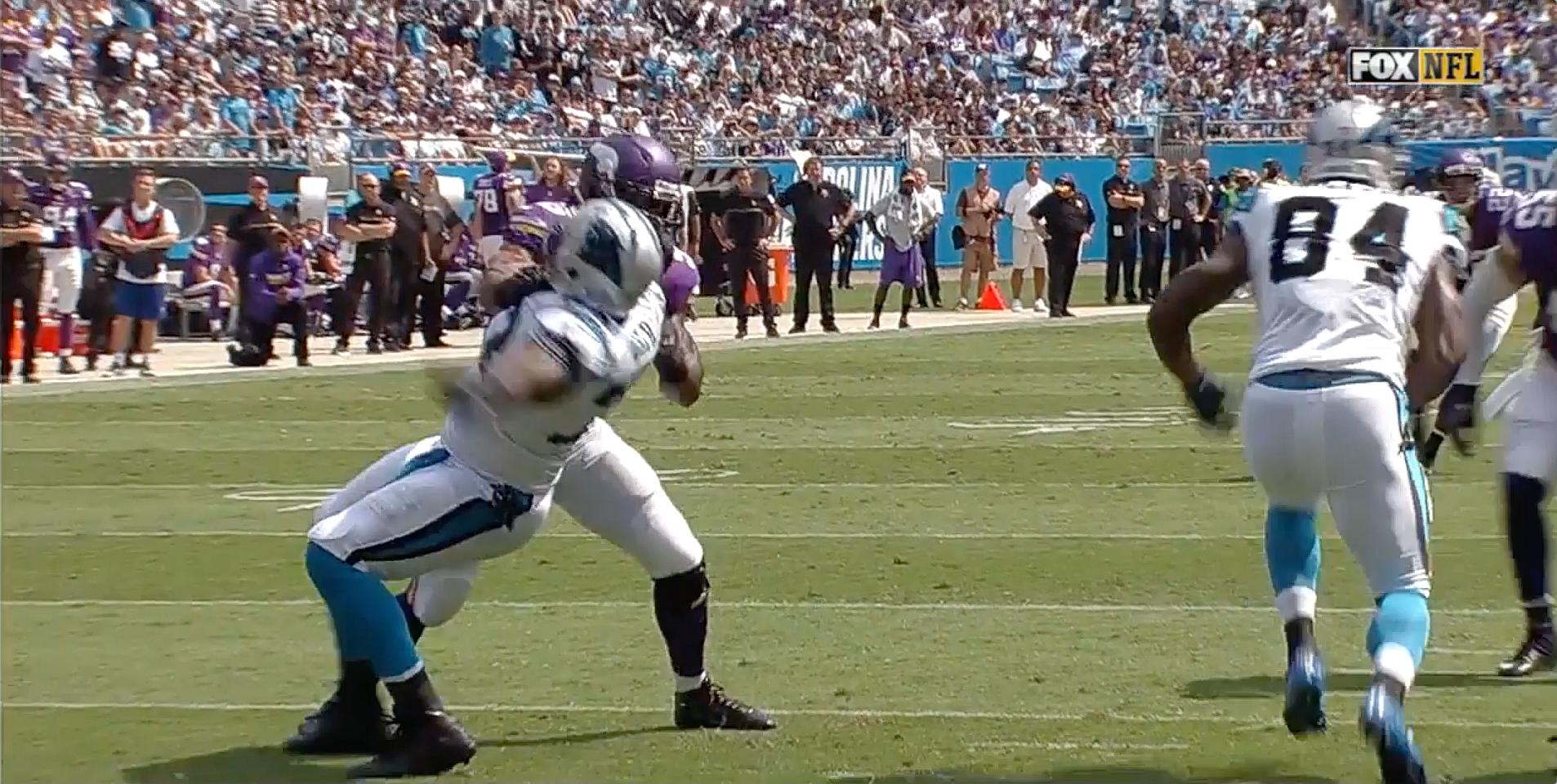 Football player in light blue jersey bends forward during game on field.