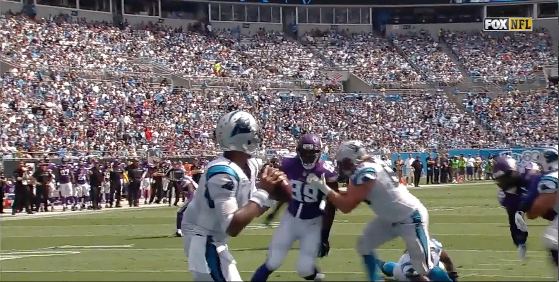 Vikings player in purple jersey attempts pass against blue-jersed defenders.