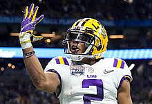 Vikings player wearing purple number 5 jersey and yellow helmet at stadium.