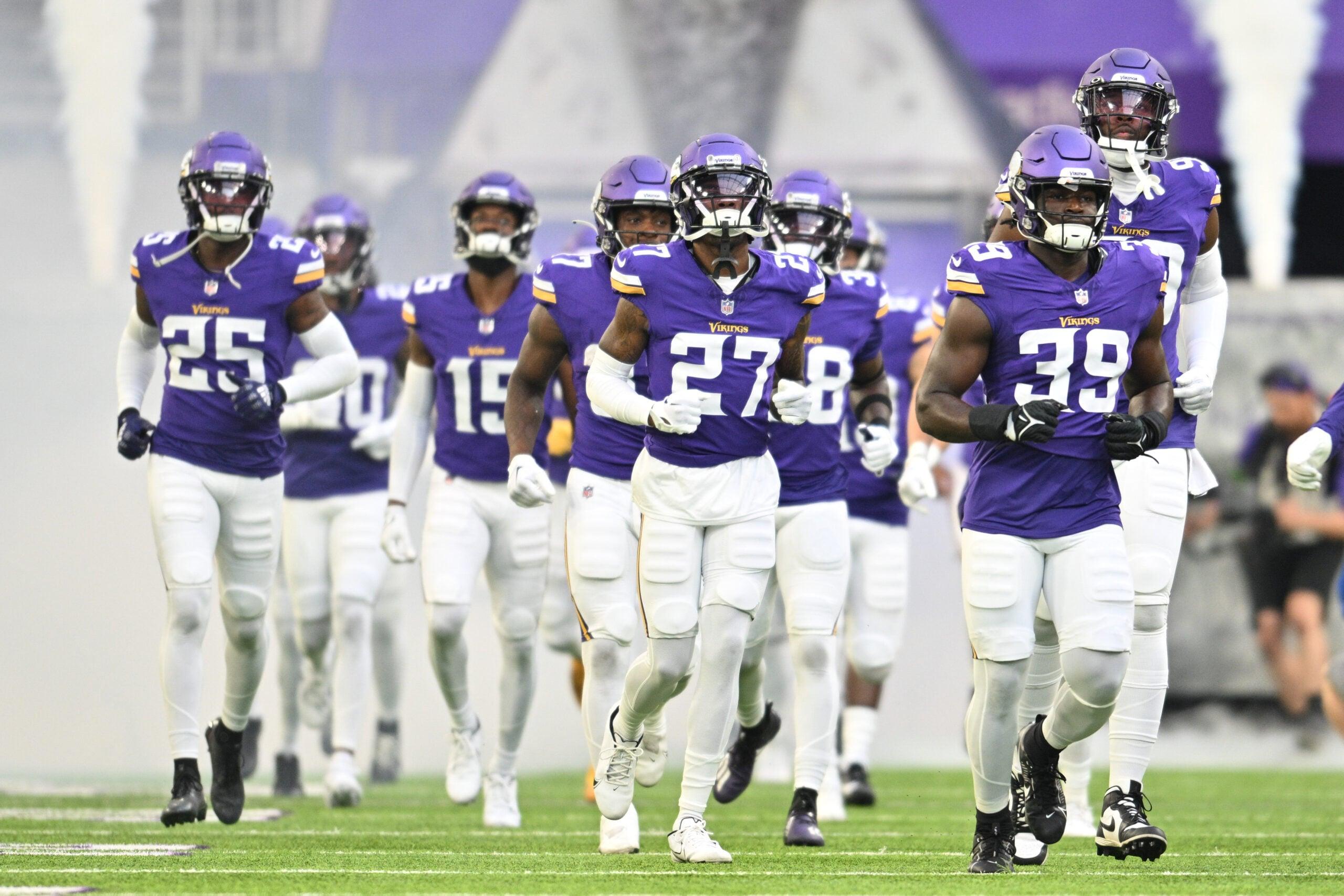 Abraham Beauplan, Kalon Barnes, and Theo Jackson lead the Minnesota Vikings onto the field at U.S. Bank Stadium before a preseason game.
