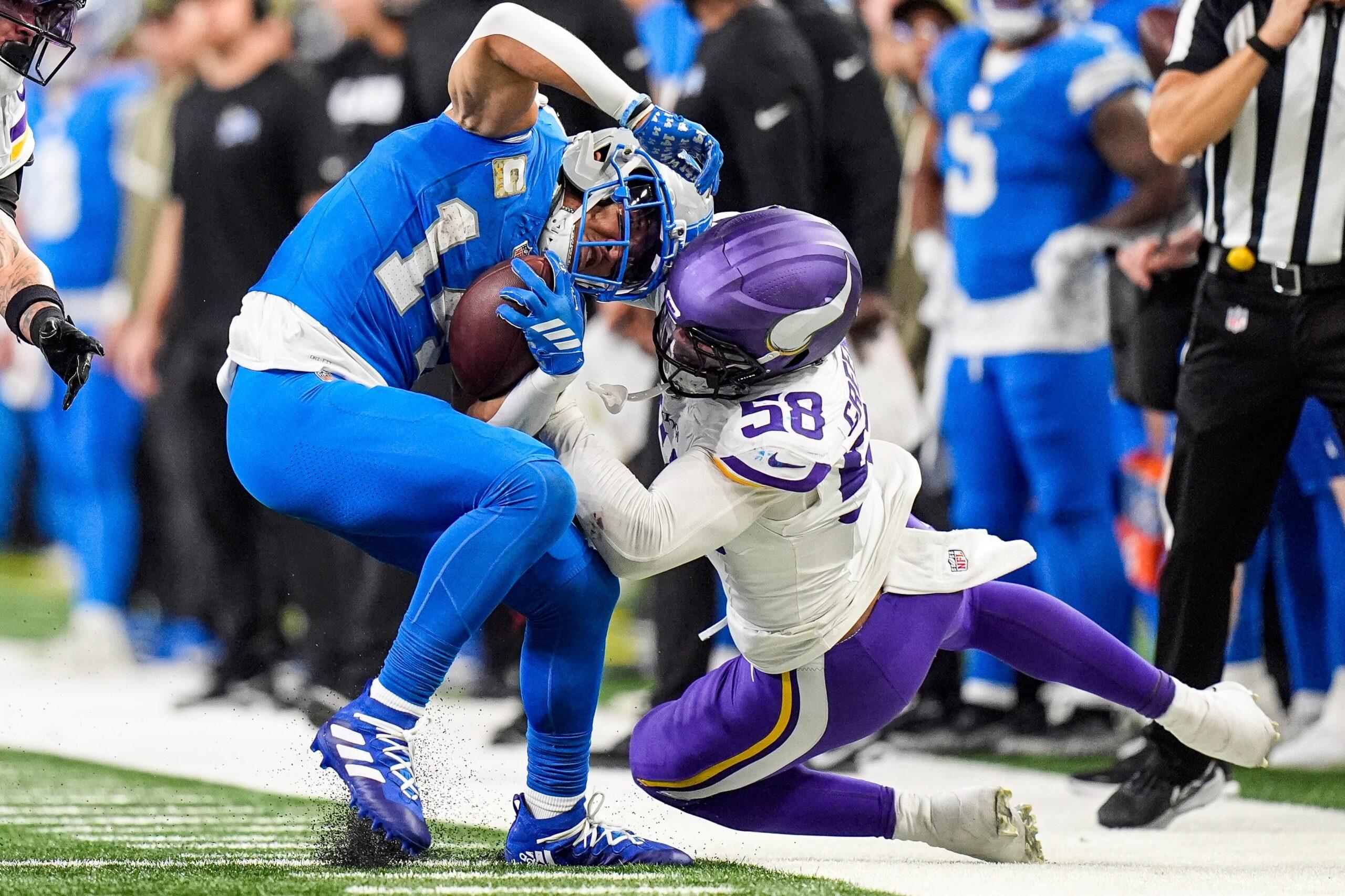 Amon-Ra St. Brown catches a pass as Jonathan Greenard closes in during Lions-Vikings action at Ford Field.