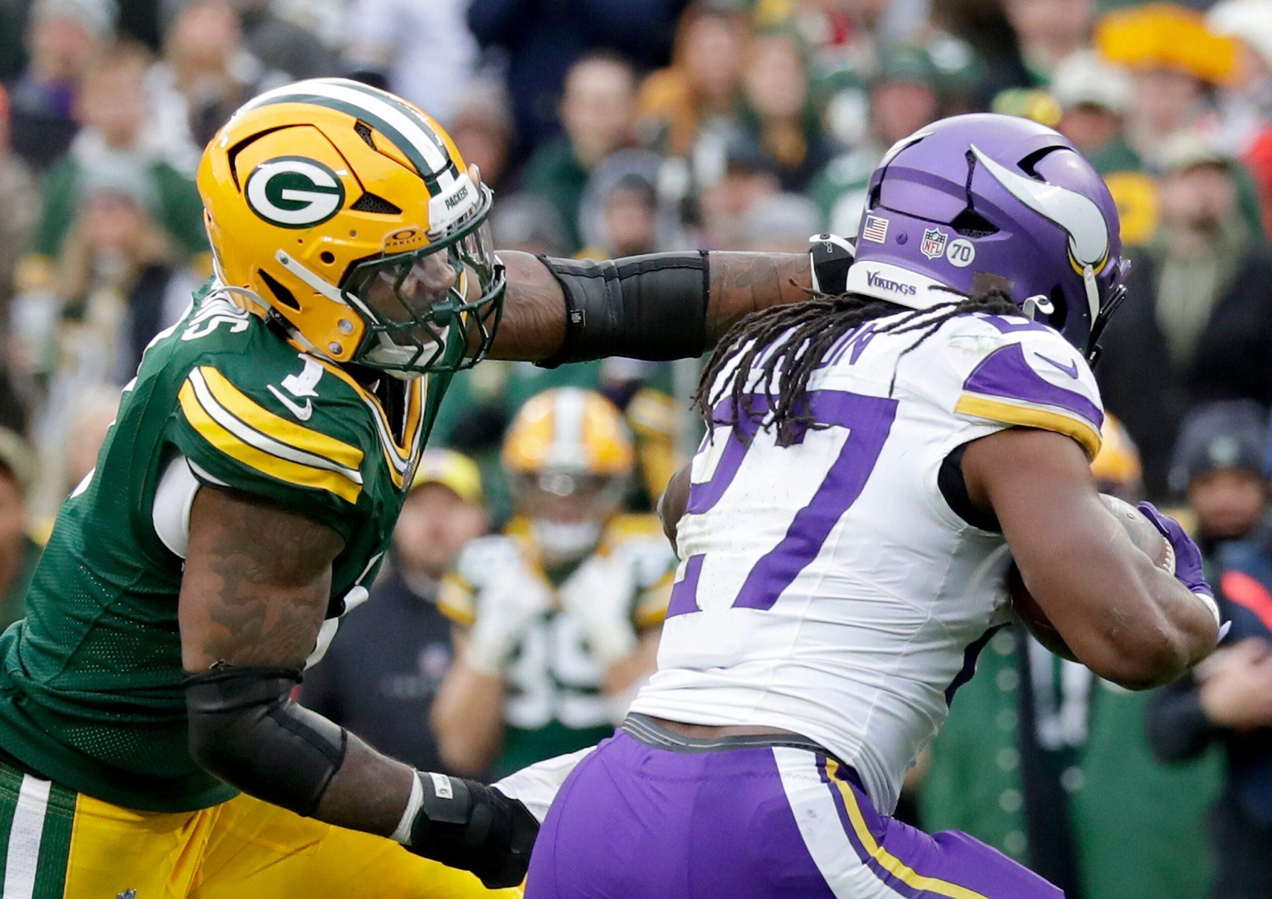 Vikings running back Jordan Mason carries the ball against Packers defender Micah Parsons at Lambeau Field.