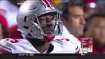 Football player wearing silver helmet and white jersey on sideline during game.