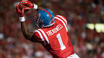 Football player in red jersey raising gloved hand during stadium game.