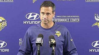 Minnesota Vikings coach speaks at podium during press conference.