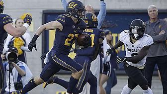 Cal football player running with ball while Colorado defender pursues during game.