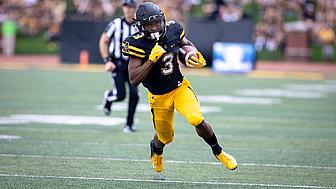 Football player in black and yellow jersey running with ball during game.