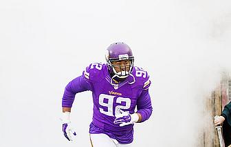 Minnesota Vikings player wearing number 92 purple jersey running with football.