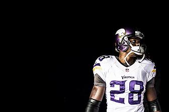Minnesota Vikings player wearing number 28 white jersey against black background.