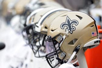 New Orleans Saints helmets lined up on the bench during a 2021 road game.