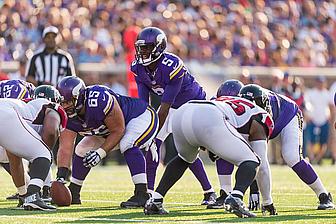 Vikings quarterback calls play at line of scrimmage during home game.