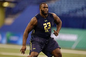 Athlete in navy and gold uniform running on indoor football field.