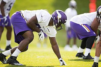Vikings player in white jersey stretches during outdoor practice session.