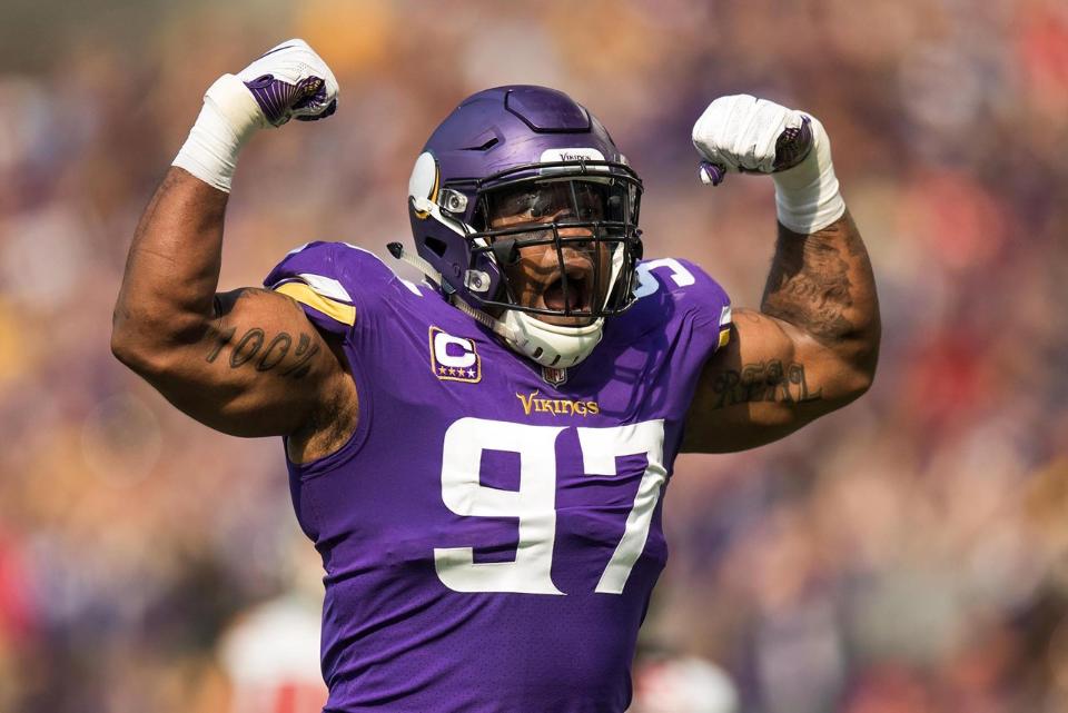 Vikings defensive player number 97 celebrates with arms raised during game.