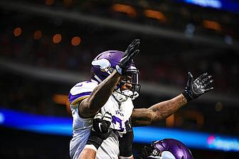 Vikings player in purple jersey celebrates with raised arms during game.