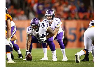 Vikings players in purple jerseys line up at scrimmage during game.