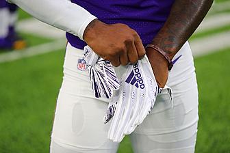 Minnesota Vikings player holding purple and white towel on field.