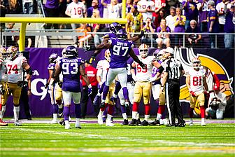 Vikings defensive players celebrate during NFL game at home stadium.