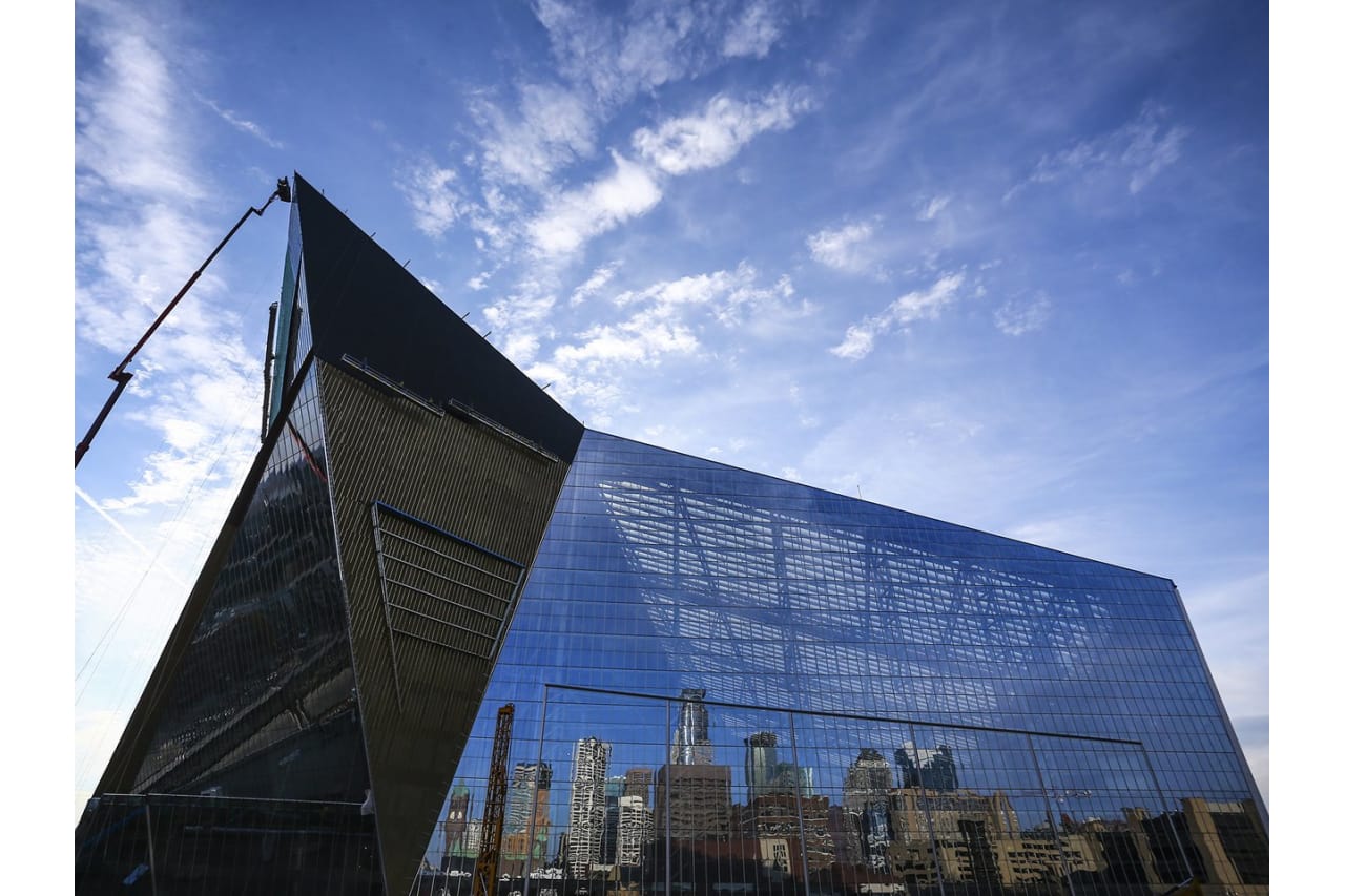 Modern glass building with city skyline reflection against blue sky.