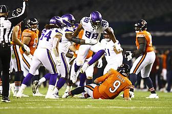 Vikings and opposing team players compete for ball during NFL game.