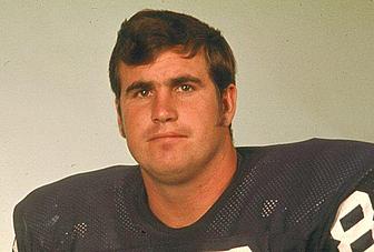 Man wearing dark NFL jersey against neutral background, professional headshot style.