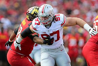 Football player in white jersey with number 57 engaged with opponent in red.