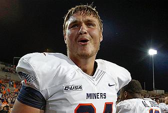 Football player wearing white UTEP Miners jersey at night game.