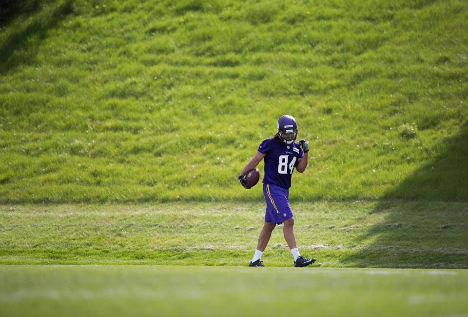Football player wearing purple jersey number 84 practicing on field.