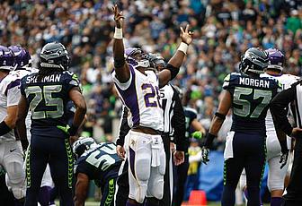 Vikings and opponent players on field during NFL game with crowd visible.