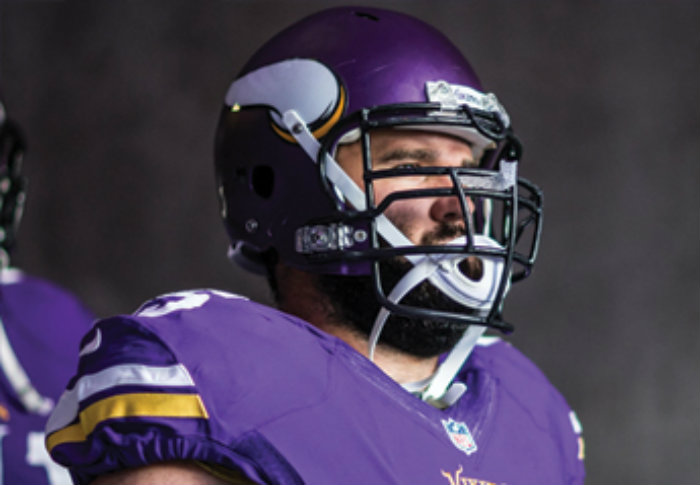 Minnesota Vikings player in purple jersey and helmet on sideline.