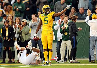Player in yellow jersey celebrates while opponent lies on field during game.