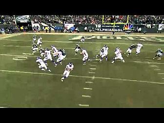 Football players in white jerseys execute offensive play on field during game.