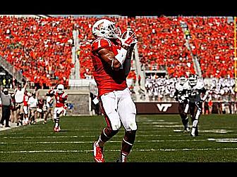 Football player in red jersey catching ball in stadium.