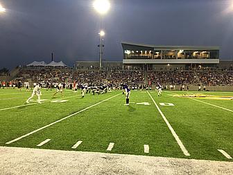 Soccer match at night under stadium lights with large crowd in stands.