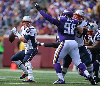 Chargers quarterback throws pass while Vikings defender jumps with arm raised.