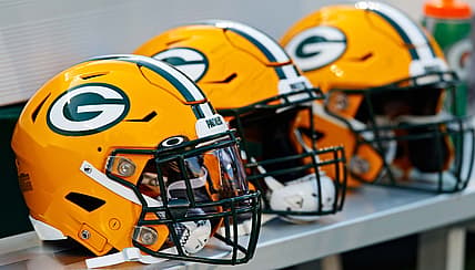Green Bay Packers helmets lined up on the sideline at Lambeau Field