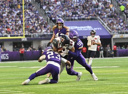 Colston Loveland is tackled by Fabian Moreau and Eric Wilson during a Bears–Vikings game at U.S. Bank Stadium.