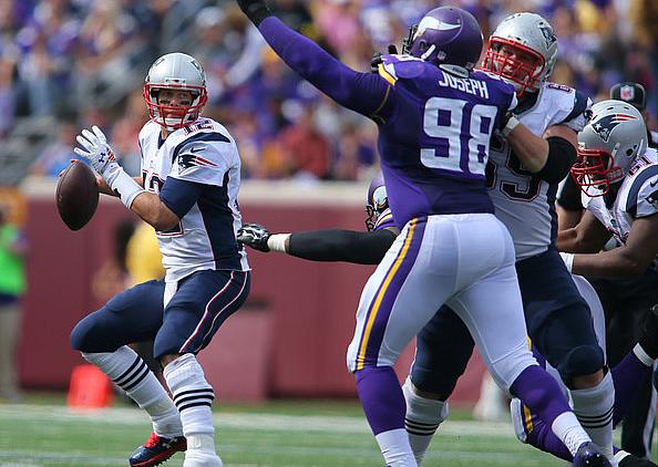 Chargers quarterback throws pass while Vikings defender jumps with arm raised.