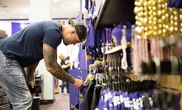 Man examining purple Vikings merchandise on retail display shelf.