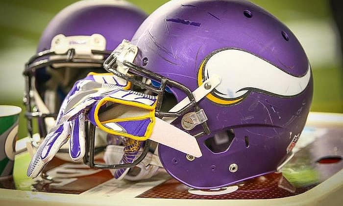 Two purple Vikings helmets with white 'V' logo displayed on field surface.