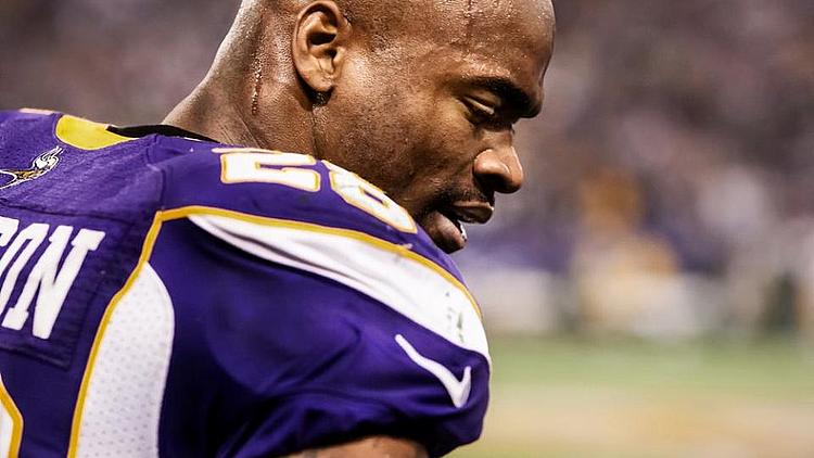 Minnesota Vikings player in purple jersey on sideline during game.