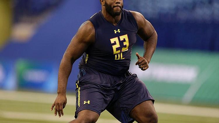 Athlete in navy and gold uniform running on indoor football field.