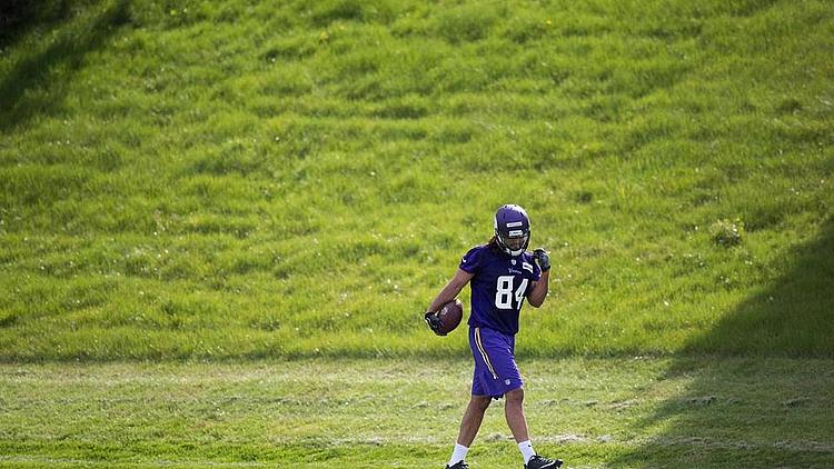 Football player wearing purple jersey number 84 practicing on field.