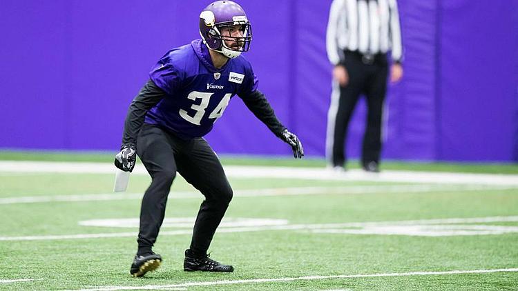 Vikings defensive player in purple jersey in defensive stance on field.