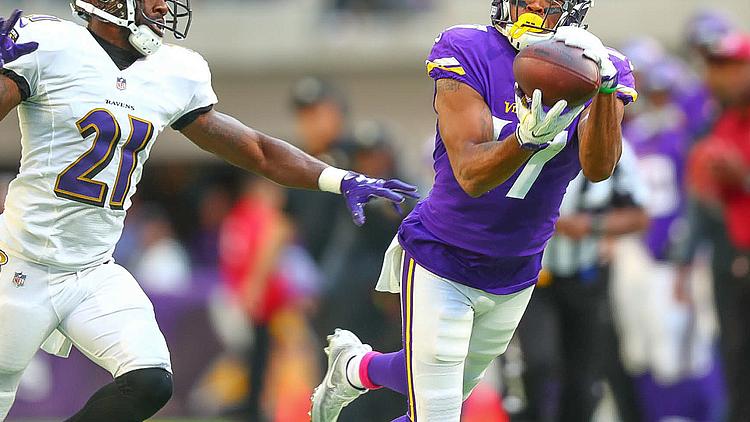 Vikings receiver catches pass while defender attempts to make tackle.