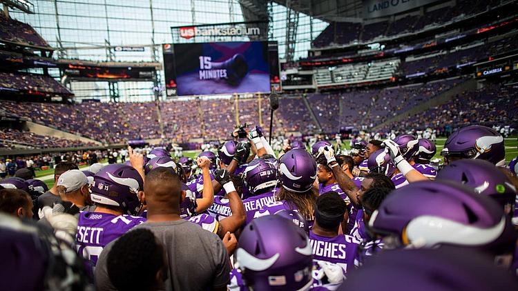 Vikings fans celebrate on field at U.S. Bank Stadium during game.