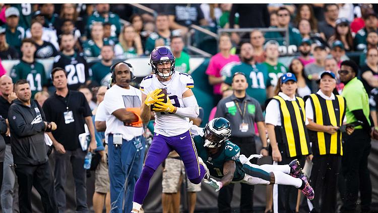 Vikings receiver in purple jersey evading defender during NFL game.