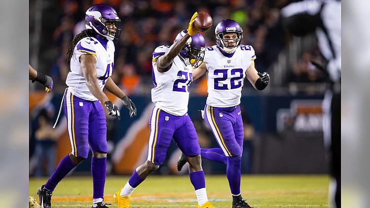 Vikings players in purple jerseys celebrate during a night game on the field.